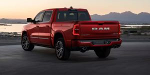 Red RAM 1500 truck viewed from the rear, driving on a road at sunset.